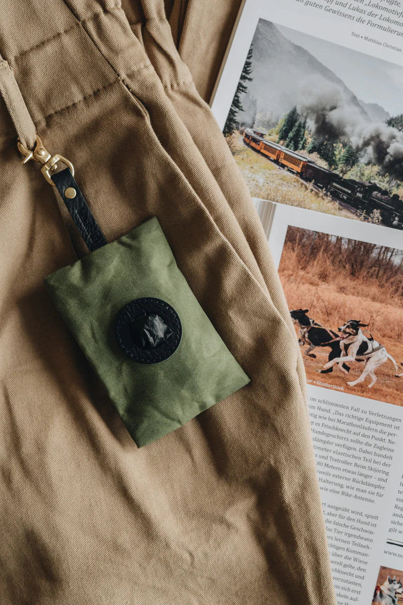 Support pour sacs NOI en toile cirée verte, attaché à un sac à dos